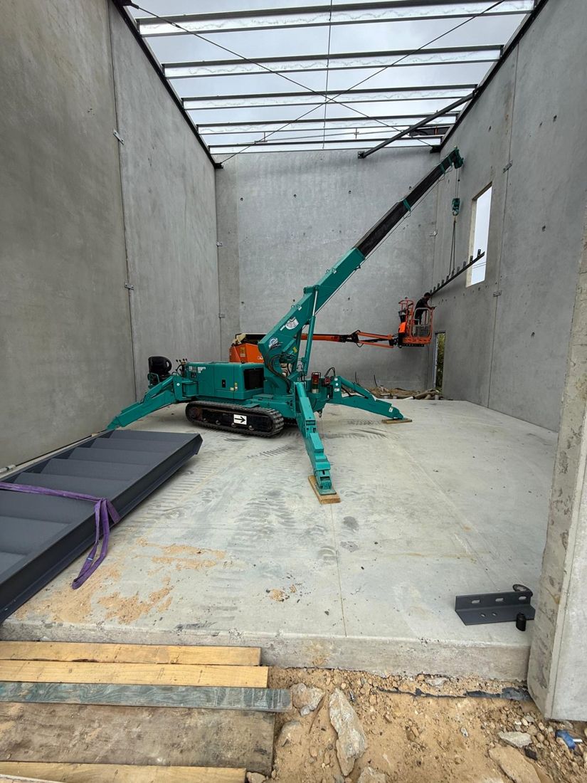 Maeda spider crane lifting steel inside a concrete building