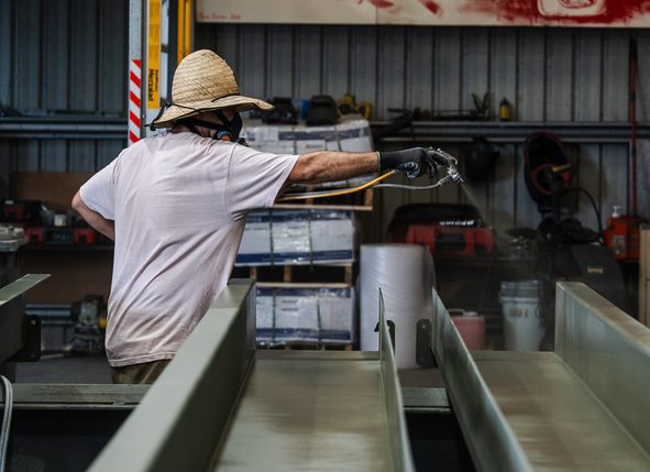 Painter spray coating steel sections